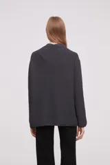 Saco abierto de tejido de punto grueso, color gris, con mangas largas y bolsillos frontales aplicados.