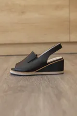 Sandalias de cuero negro con taco corrido y plataforma de doble tono. Cuenta con capellada envolvente con recortes laterales elásticos y tira trasera slingback.