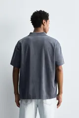 Polo de manga corta con cuello solapa y cierre frontal de tres botones. Presenta un diseño de corte relajado con acabado de efecto lavado.