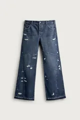 Jeans flare fit de denim azul oscuro con roturas y costuras decorativas en las perneras. Tiro medio y diseño de cinco bolsillos.