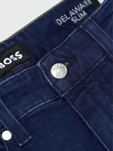 Jeans de corte ajustado en denim azul oscuro, con etiqueta de la marca Boss cosida en el bolsillo trasero y remaches metálicos grabados.