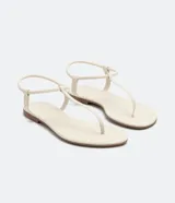 Sandalia plana de dedo color beige con tiras finas y cierre elástico en el talón. Diseño minimalista con puntera redonda y suela plana de la marca Satinato.