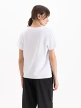 Remera de algodón pima blanco, de corte regular y escote redondo, con un diseño gráfico frontal que incluye una figura estilo Buda rodeada de flores y jarrones sobre rayas marineras.