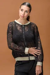 Campera tipo bomber confeccionada en encaje negro con diseño floral. Presenta cierre frontal completo, cuello, puños y ruedo en tejido elástico color dorado brillante.