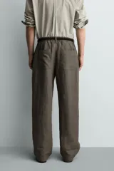 Pantalón straight fit color verde militar, confeccionado en lino, con cintura con trabillas, cierre frontal con cremallera y botón, y bolsillos laterales.