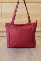 Cartera tipo tote de cuero vacuno negro con doble asa de hombro, panel superior liso y bolsillo exterior frontal con textura símil cocodrilo y costuras visibles en contraste.