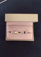 Set de dos anillos de plata 925 que incluye una alianza de diseño liso y plano y un anillo con piedra central azul en forma de gota rodeada de zirconias brillantes, con pavé en el aro.