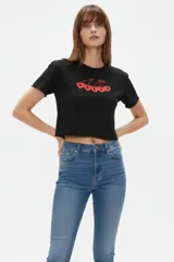 Remera cropped de algodón negra con cuello a la base, mangas cortas y estampado frontal de cerezas con la palabra "HELLO".