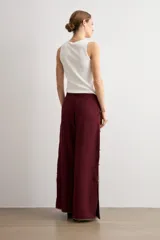 Pantalón ancho color bordó de talle alto, con abertura lateral decorada con ribete contrastante y cierre de botones tipo nudo chino.