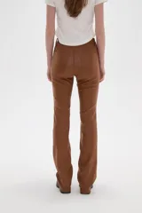 Pantalon de corte flare en color negro, con acabado engomado, tiro medio y cierre frontal con botón y cremallera.