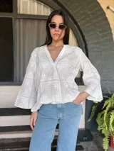 Blusa blanca de broderie con cuello mao y escote en V, mangas largas acampanadas y bordados calados.