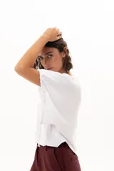 Blusa blanca de corte holgado y diseño minimalista, con mangas cortas tipo murciélago que presentan un detalle de fruncido lateral con cordón ajustable.