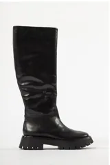 Botas bucaneras de cuero negro con caña alta, suela track robusta y cierre lateral.