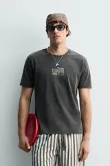 Camiseta de corte relajado con efecto lavado, cuello redondo y manga corta. Presenta estampados con textos en contraste en el frente.