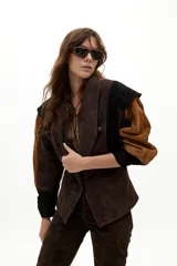 Chaqueta de gamuza con diseño de paneles en colores marrón, chocolate y negro. Presenta hombros estructurados, corte entallado en la cintura y botones forrados al tono.