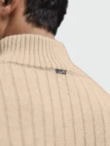 Cardigan de lana color beige con cierre frontal, cuello alto y diseño acanalado.