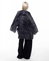 Kimono negro con efecto lavado, confeccionado en algodón. Tiene corte amplio, mangas 3/4, bolsillos laterales y cierre frontal con hebilla metálica.