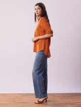 Camisa color beige de tencel, marca Hester & Orchand, con cuello con solapa, escote en V, abertura central con botones y bolsillos delanteros. Las mangas son largas y regulables con presilla y botón.