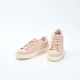 Zapatillas bajas de cuero color rosa pálido con cordones y suela blanca.