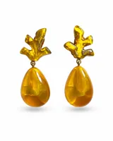 Caravanas artesanales francesas de diseño moderno, compuestas por una pieza superior con forma abstracta similar a coral y un colgante inferior en forma de lágrima, elaboradas en resina translúcida de color ámbar y amarillo, con cierre de clip.