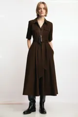 Vestido midi de cuello solapa y escote en pico, con manga corta con vuelta. Presenta bolsillos laterales ocultos, solapas decorativas en el pecho y cierre frontal con botones. Incluye cinturón de lazada en el mismo tejido.
