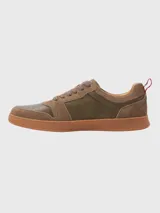 Sneaker de hombre en tonos marrones, confeccionada en una combinación de cuero y descarne. Presenta un diseño de paneles con cordones al tono, suela de goma color caramelo y un detalle de cinta tricolor en el talón.