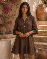 Vestido corto verde militar de lino, con cuello mao, escote en V con botones, mangas tres cuartos acampanadas con volados y falda con volado en el ruedo.