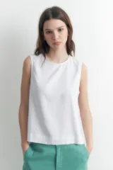 Blusa blanca sin mangas confeccionada en lino, con corte recto y aberturas laterales ajustables con lazos.