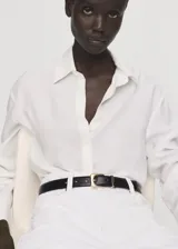 Camisa de lyocell color blanco, con cuello camisero, manga larga con puños abotonados, diseño recto y cierre frontal con botones ocultos.