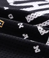 Remera oversized de poliéster calado estilo mesh, color negro con detalles en blanco y dorado, cuello redondo y mangas cortas. Presenta estampa frontal localizada, numeración y estrellas aplicadas en los hombros.