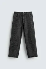 Pantalón de corte baggy fit confeccionado en tejido de algodón con textura y efecto lavado. Presenta diseño de cinco bolsillos, cierre frontal con cremallera y botón.