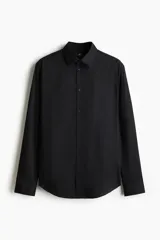 Camisa negra de manga larga, corte slim fit, confeccionada en tejido elástico de mezcla de algodón. Presenta cuello italiano, tapeta lisa con botones y bajo redondeado.