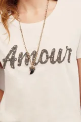 Remera de algodón blanca de manga corta y cuello redondo, con aplicación de pedrería formando la palabra "Amour" en el frente.