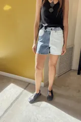 Short de jean de tiro alto con diseño color block, una pierna en denim azul y la otra en denim blanco.