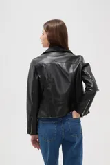 Campera estilo biker de cuero sintético color negro, con cierre frontal cruzado, solapas con botones a presión y bolsillos laterales con cierre.