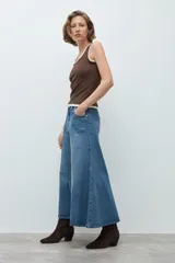 Falda midi de jean en color azul medio, con diseño de paneles verticales y corte acampanado. Presenta cierre frontal con botón y bolsillos laterales.