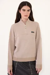 Sweater negro de punto con cuello alto y cierre frontal parcial de cremallera, de manga larga y diseño holgado con hombros caída.