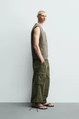 Chaleco acolchado de algodón color verde militar, de corte relaxed fit, con cuello en V, cierre frontal con cremallera y bolsillos de parche en la cadera. Presenta diseño acolchado con pespuntes ondulados y efecto lavado.