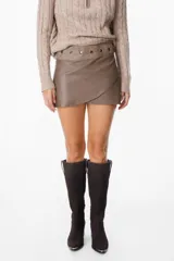 Mini falda tipo cruzada confeccionada en cuero, con detalle de cintura con tachas metálicas.