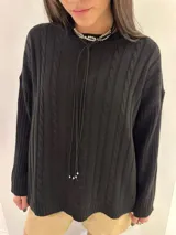 Sweater tejido color negro, con cuello redondo y diseño de ochos en el frente y mangas con diseño a rayas verticales.