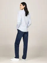 Camisa celeste de popelín de algodón orgánico, corte regular, cuello inglés, puños con botón, bajo redondeado y logo de Tommy Hilfiger bordado en el pecho.