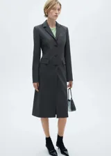 Blazer entallado de diseño largo, con cuello de solapa con muesca, cierre frontal de botones y bolsillos de solapa. Cuenta con un bolsillo de ribete en el pecho y mangas largas con puños abotonados.