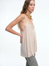 Top lencero de tirantes finos, color blanco, con escote en V decorado con encaje. Presenta una silueta holgada y liviana.