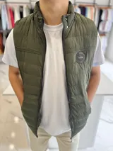 Chaleco puffer de nylon color verde militar, con cuello alto, cierre frontal y capucha desmontable. Presenta un parche circular con la inscripción "Turk" en el pecho.