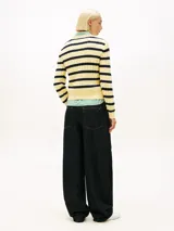 Sweater de punto de algodón orgánico con cuello redondo, diseño de rayas horizontales en amarillo y azul oscuro, y detalle de tejido de cable. Presenta el logo bordado en el pecho de la marca Tommy Hilfiger.