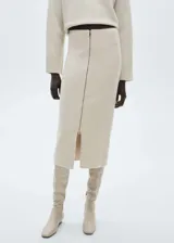 Falda midi de tejido de punto en color beige, con diseño recto de tiro medio y cierre de cremallera frontal que crea una abertura en el bajo.