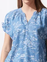 Blusa de lyocell color celeste con estampado de motivos playeros en blanco. Tiene cuello a la base con escote en V, mangas cortas con volados y detalle fruncido en mangas y espalda.