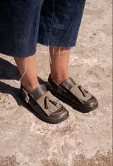 Mocasines de cuero marrón con aplique de cuero verde con borlas.