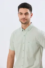 Camisa de manga corta confeccionada en mezcla de lino y algodón, color beige, con cuello camisero abotonado, bolsillo frontal en el pecho y cierre de botones.