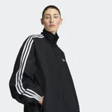 Campera deportiva Adidas modelo Firebird Adilenium, de color negro con las clásicas tres tiras blancas en las mangas, cuello alto y cierre frontal.